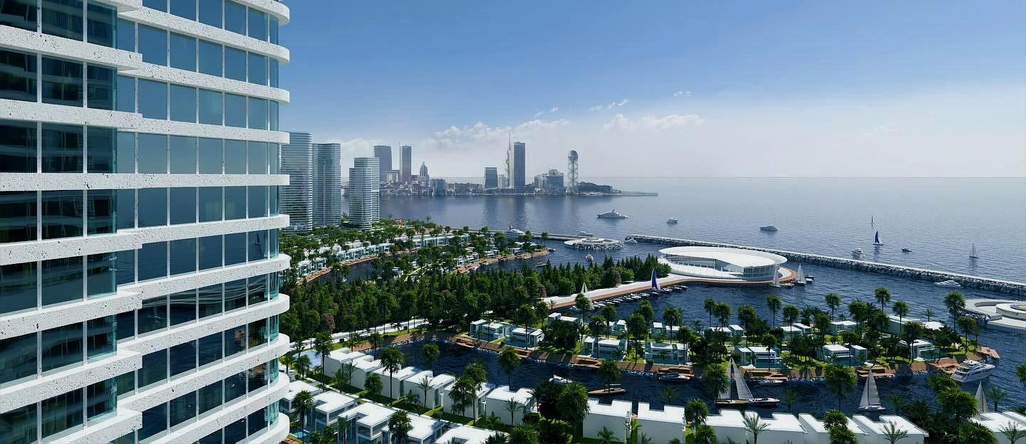 3D-визуализация прибрежного жилого комплекса с высотным зданием на переднем плане, виллами и мариной для яхт на фоне городского пейзажа.