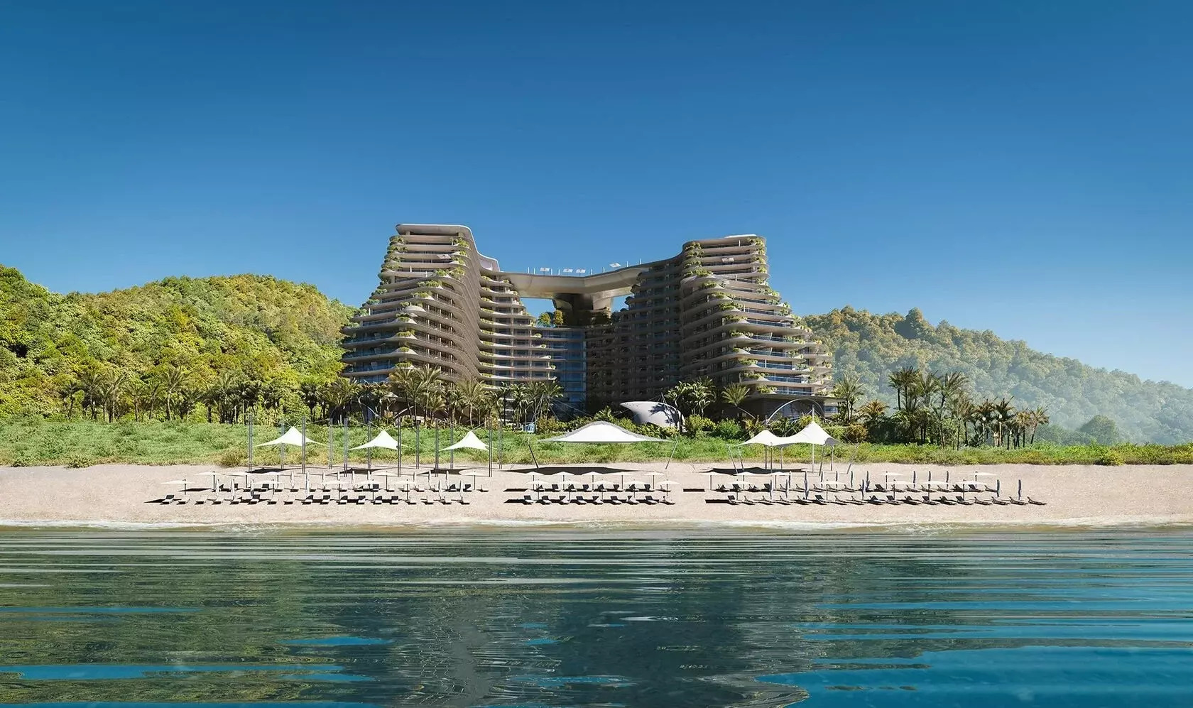 3D-визуализация масштабного жилого или гостиничного комплекса с уникальной архитектурой, расположенного на первой береговой линии с оборудованным пляжем и зелеными холмами на фоне.